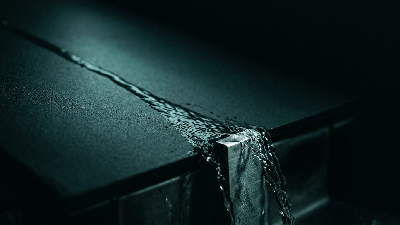 Illustration for this article: A single AI agent's mistake can derail the chain. Water sheeting down a matte dark surface, breaking around an unseen obstruction.