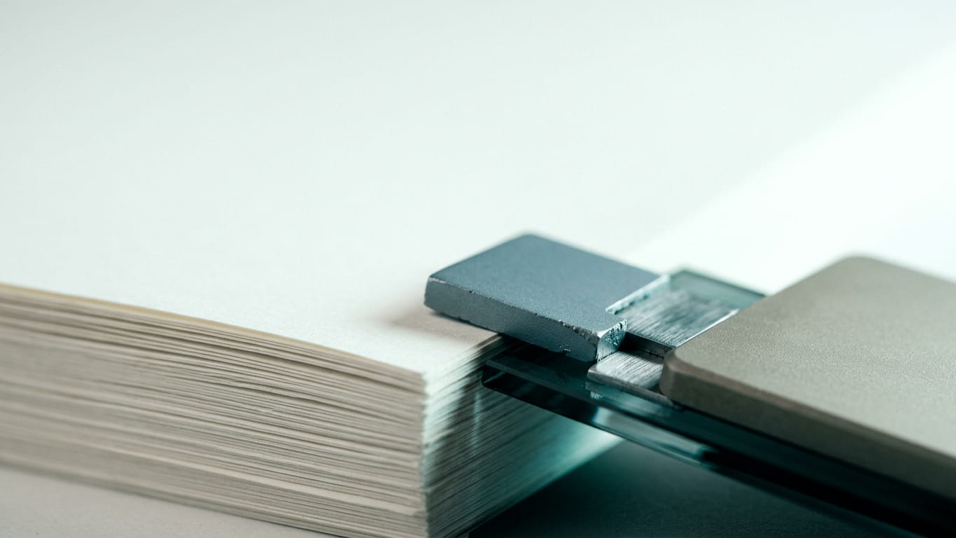 Illustration for this article: AI memory is the new data-leak vector. The cut edges of a thick stack of blank paper, fanned slightly, raking light along the fibres.