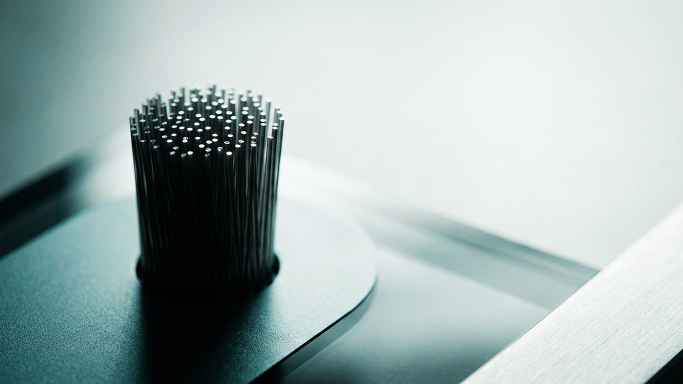 Illustration for this article: AI procurement terms become hard selection criteria. Optical fibre ends clustered together, each carrying a pinpoint of light in near darkness.