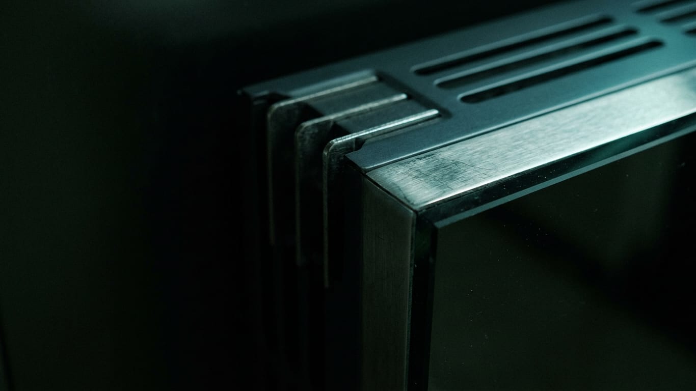 Illustration for this article: Claude Opus 5's efficiency gains. A ventilation grille in deep shadow, cold air distorting the light passing through it.
