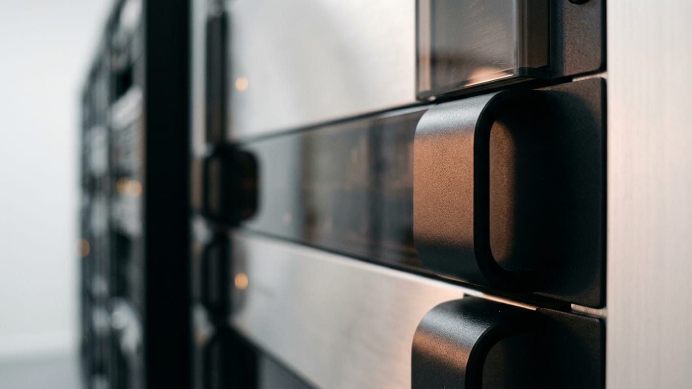 Illustration for this article: Evidence-based hallucination detection at AWS, Collibra. Rows of dark unbranded rack equipment receding down a narrow aisle, lit only by their own indicator glow.