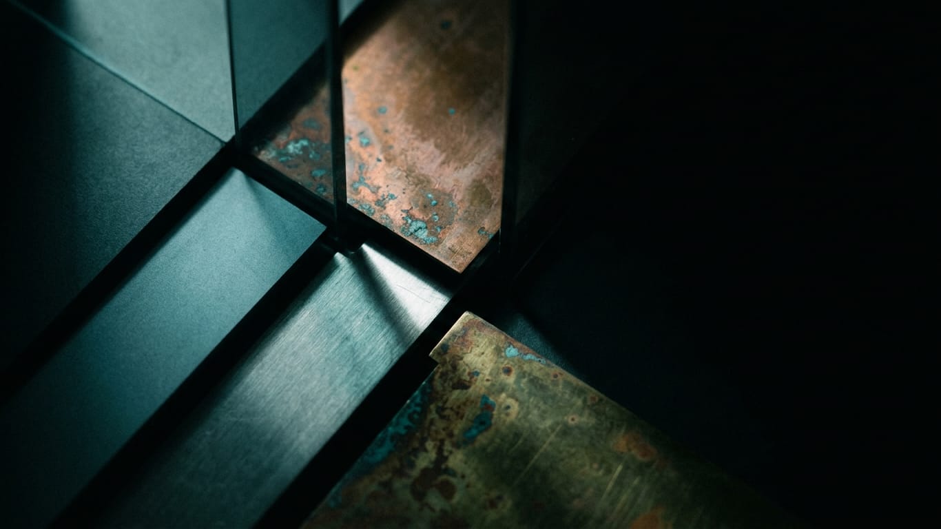 Illustration for this article: FairStress shows equal AI outcomes do not prove fair. Oxidised copper and patinated brass sheet, corrosion blooming across the surface.