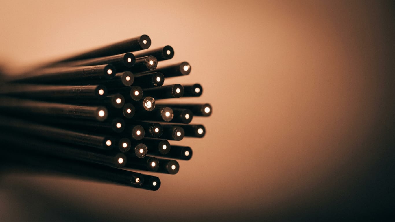 Illustration for this article: Hidden instructions in documents steer LLM judgements. Optical fibre ends clustered together, each carrying a pinpoint of light in near darkness.