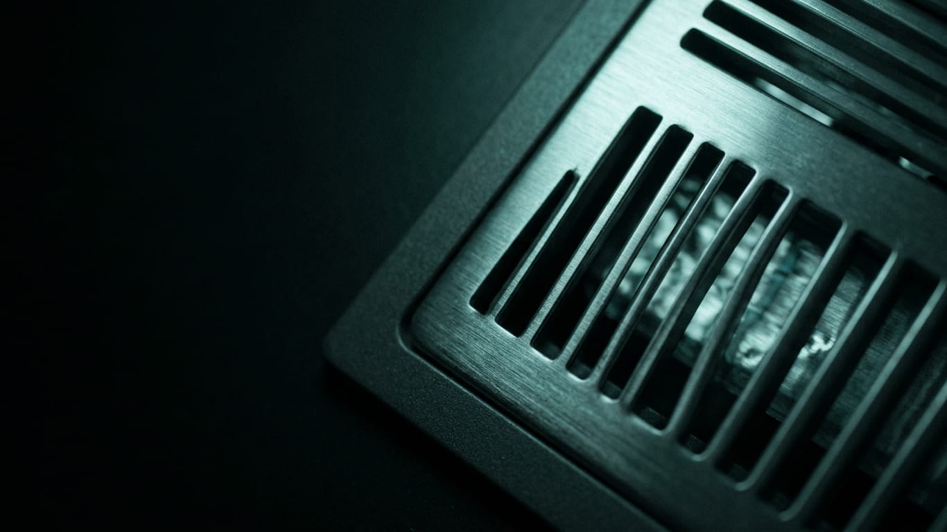 Illustration for this article: IETF draft standard for AI audit trails. A ventilation grille in deep shadow, cold air distorting the light passing through it.