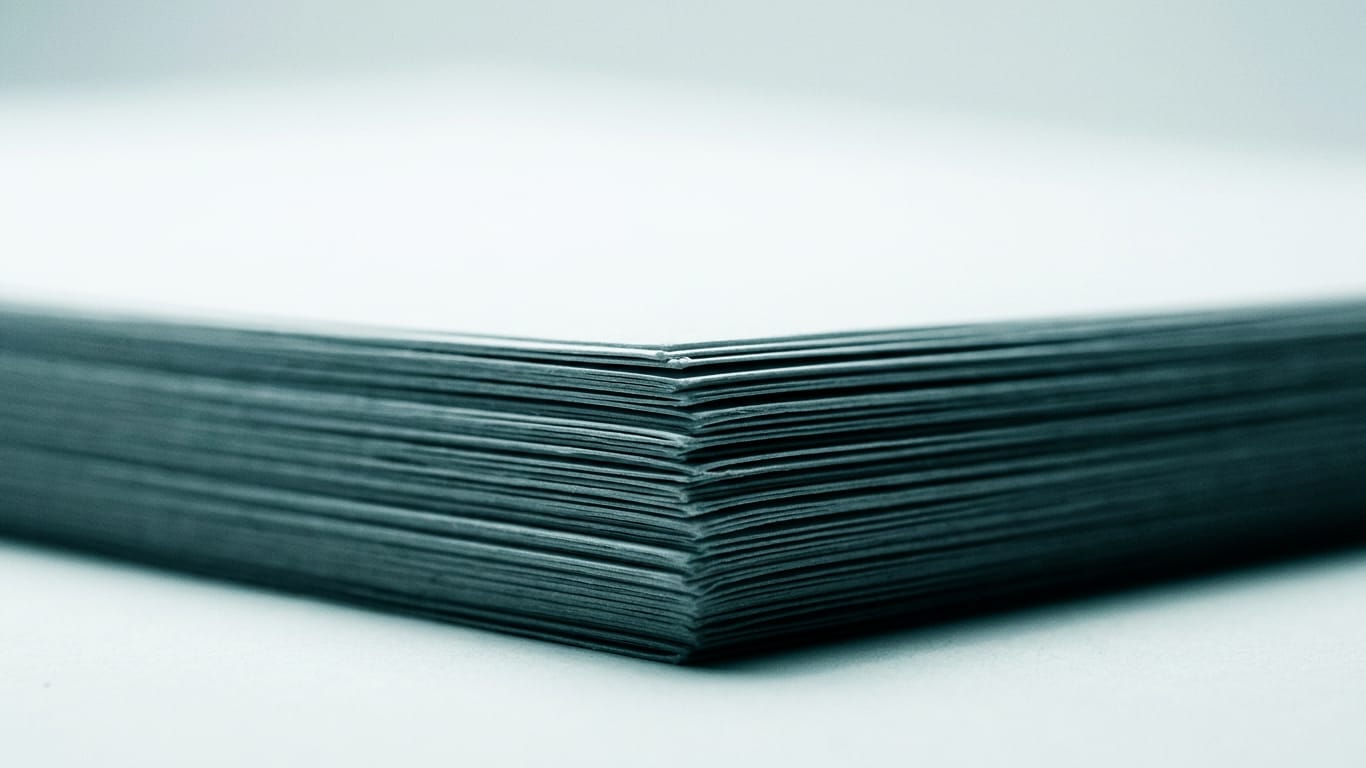 Illustration for this article: Professional secrecy in AI practice has become a design question. The cut edges of a thick stack of blank paper, fanned slightly, raking light along the fibres.