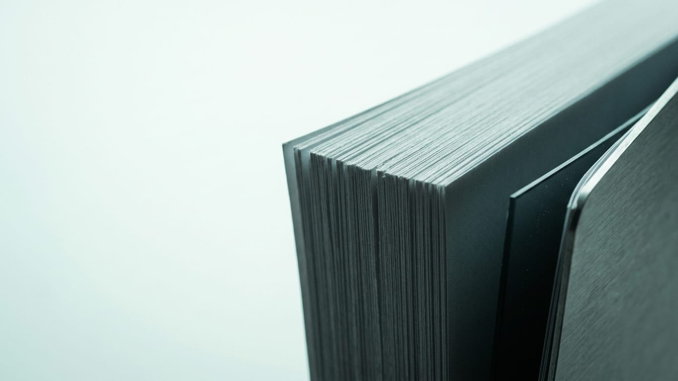 Illustration for this article: Separation of duties in autonomous AI has become a design question. The cut edges of a thick stack of blank paper, fanned slightly, raking light along the fibres.