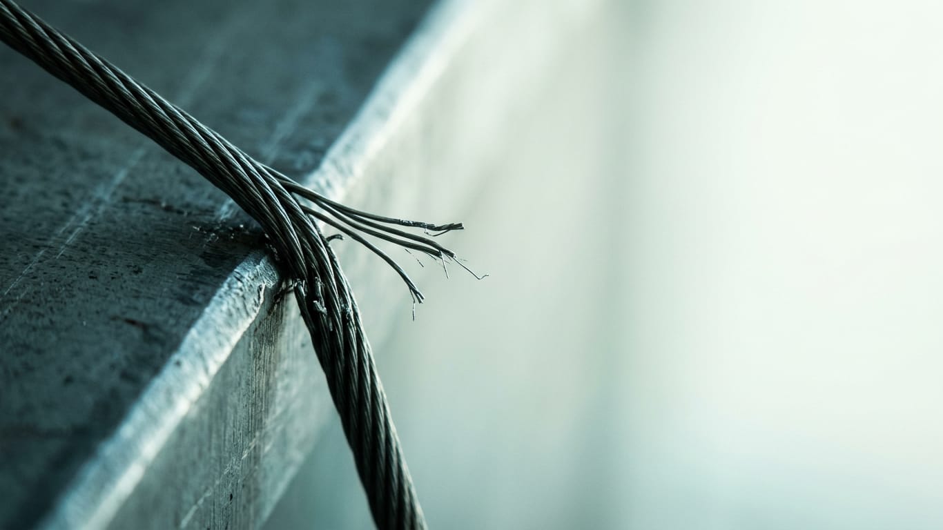 Illustration for this article: Uber fined for deactivation without human intervention. A steel cable under visible tension, strands separating where it passes over an edge.