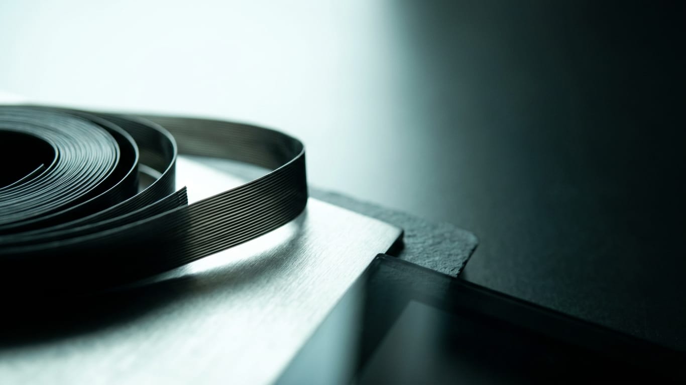 Illustration for this article: White & Case buys into AI contract platform Clauze. A coil of unbranded ribbon cable unspooling across a matte floor into darkness.