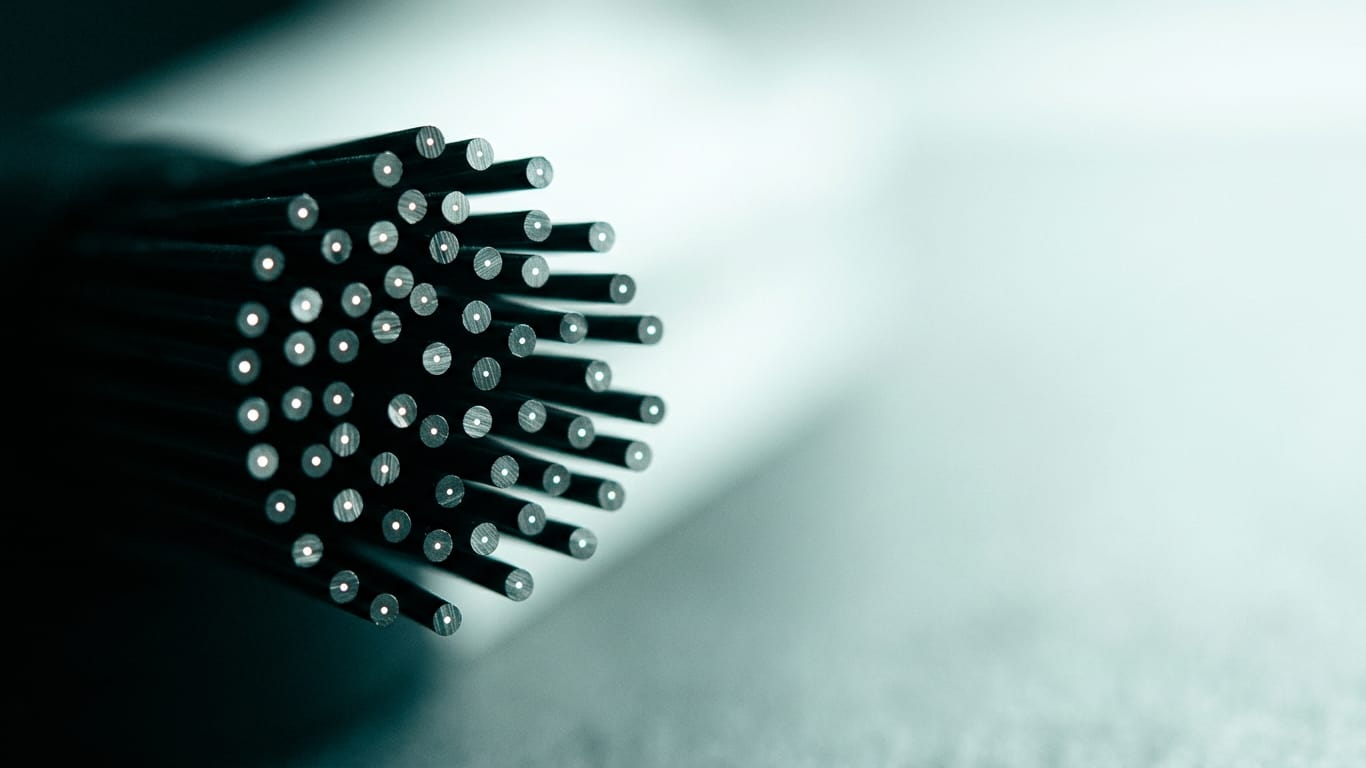 Illustration for this article: Who is liable for an AI error? How the law divides responsibility in 2026. Optical fibre ends clustered together, each carrying a pinpoint of light in near darkness.